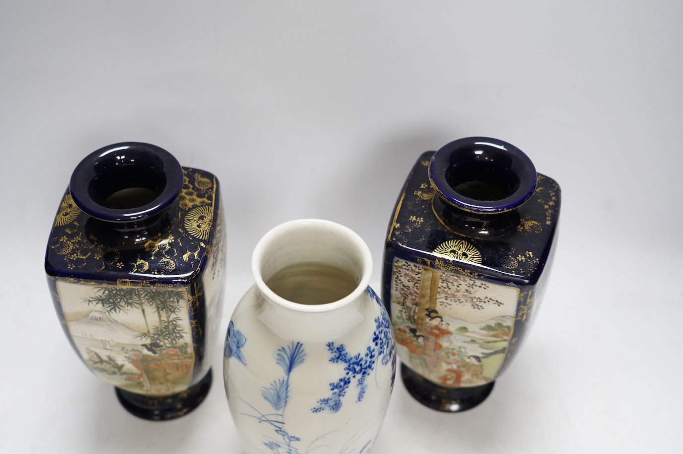 A pair of Japanese satsuma pottery vases and a blue and white Meiji Arita vase, largest 24cm high. Condition - fair